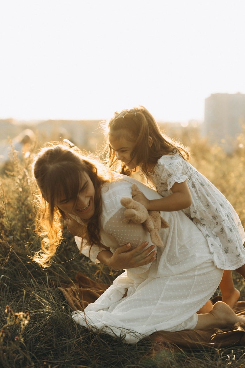 Mother and daughter laughing together in a sunlit field